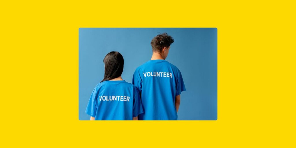 Deux bénévoles portant des t-shirts bleus marqués « Volunteer », symbolisant l’engagement bénévole au sein d’une organisation.
