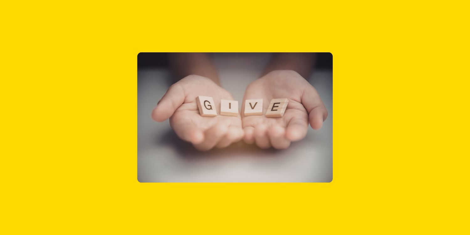 Mains ouvertes tenant des lettres formant le mot « Give », symbolisant le don, la générosité et la philanthropie.